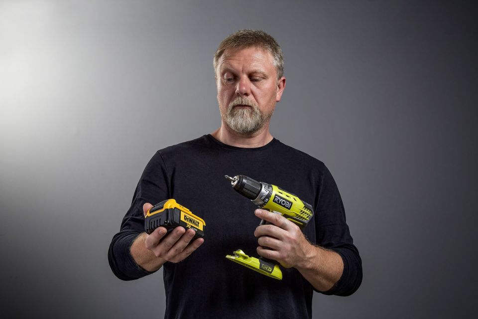 Man staring at DeWalt battery and Ryobi drill