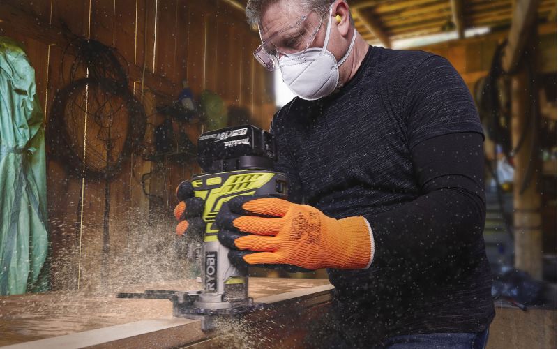 Man cutting groove in wood with power tool safety equipment on