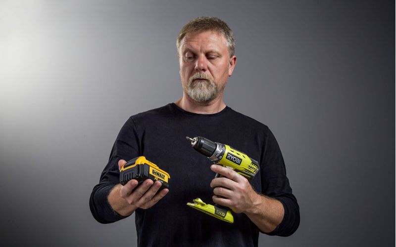 Man staring at DeWalt battery and Ryobi drill