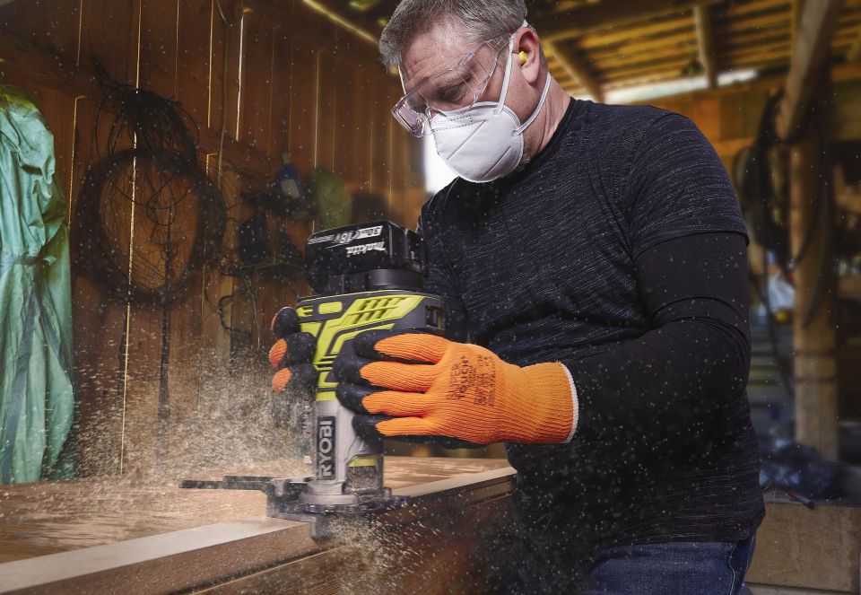 Man cutting groove in wood with power tool safety equipment on